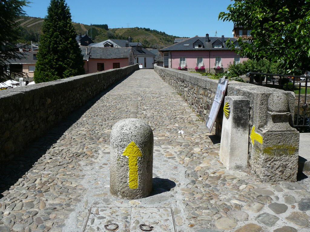 Des flèches jaunes indiquent le chemin à prendre sur une chemin de pierres.