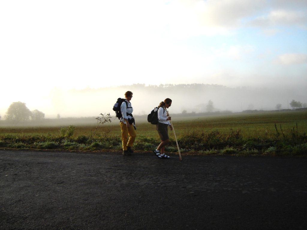 Deux pèlerins près d'un champ. Du brouillard au loin.